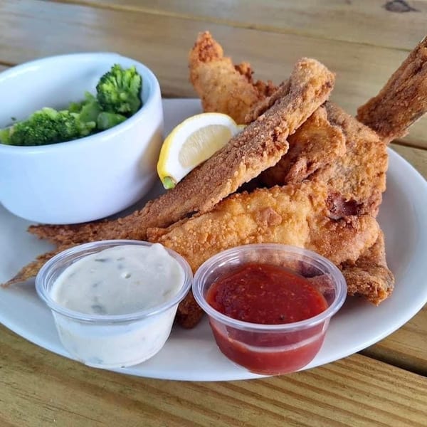 Fried fish with tails, a lemon wedge, broccoli, tartar sauce, and cocktail sauce on a white plate.